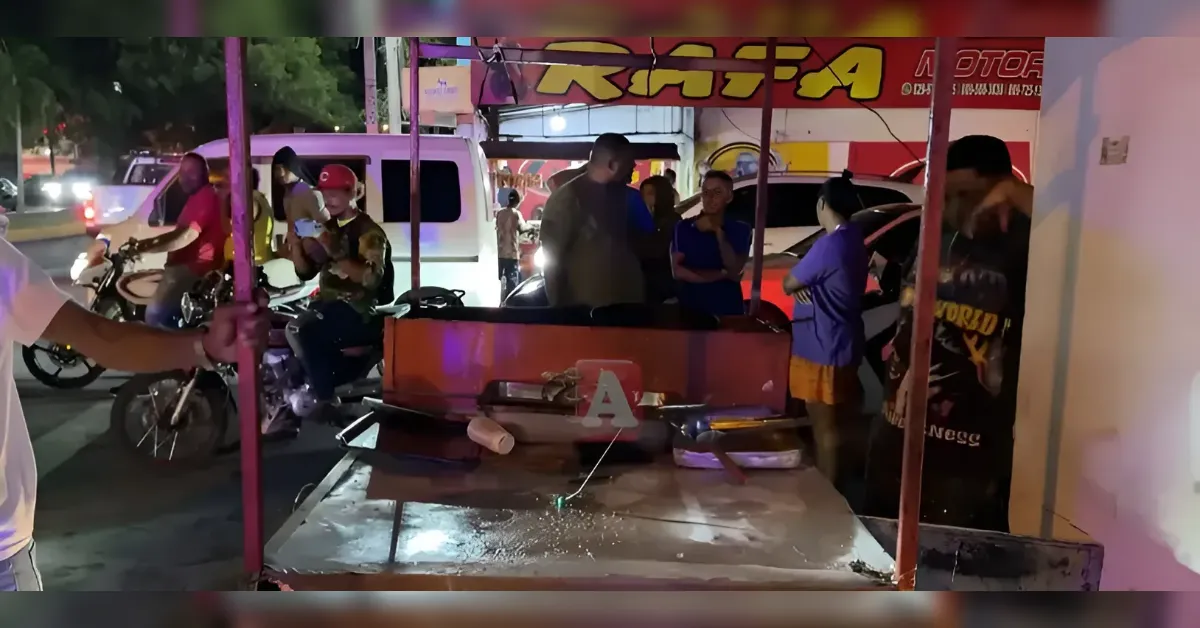 Nighttime street food stall with a red grill on a metal cart; several people stand nearby with motorcycles and a van in the background