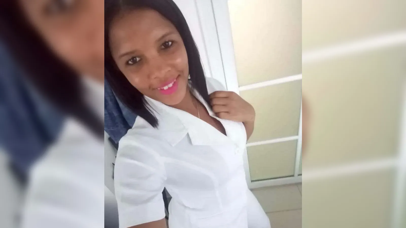 Young woman taking a selfie, smiling at the camera in a white blouse indoors
