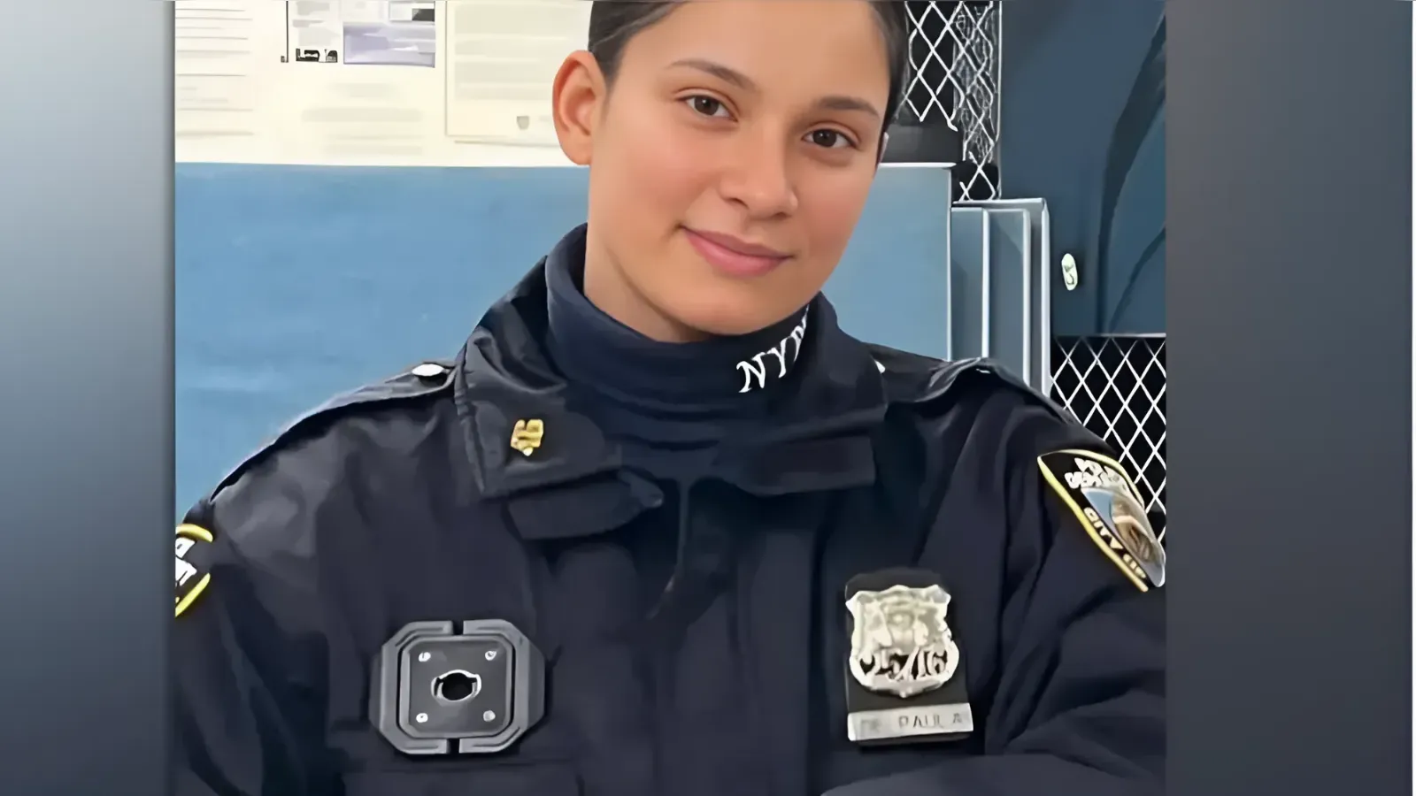 Female police officer in a dark uniform, with a badge on the chest and NYPD collar text, smiling at the camera