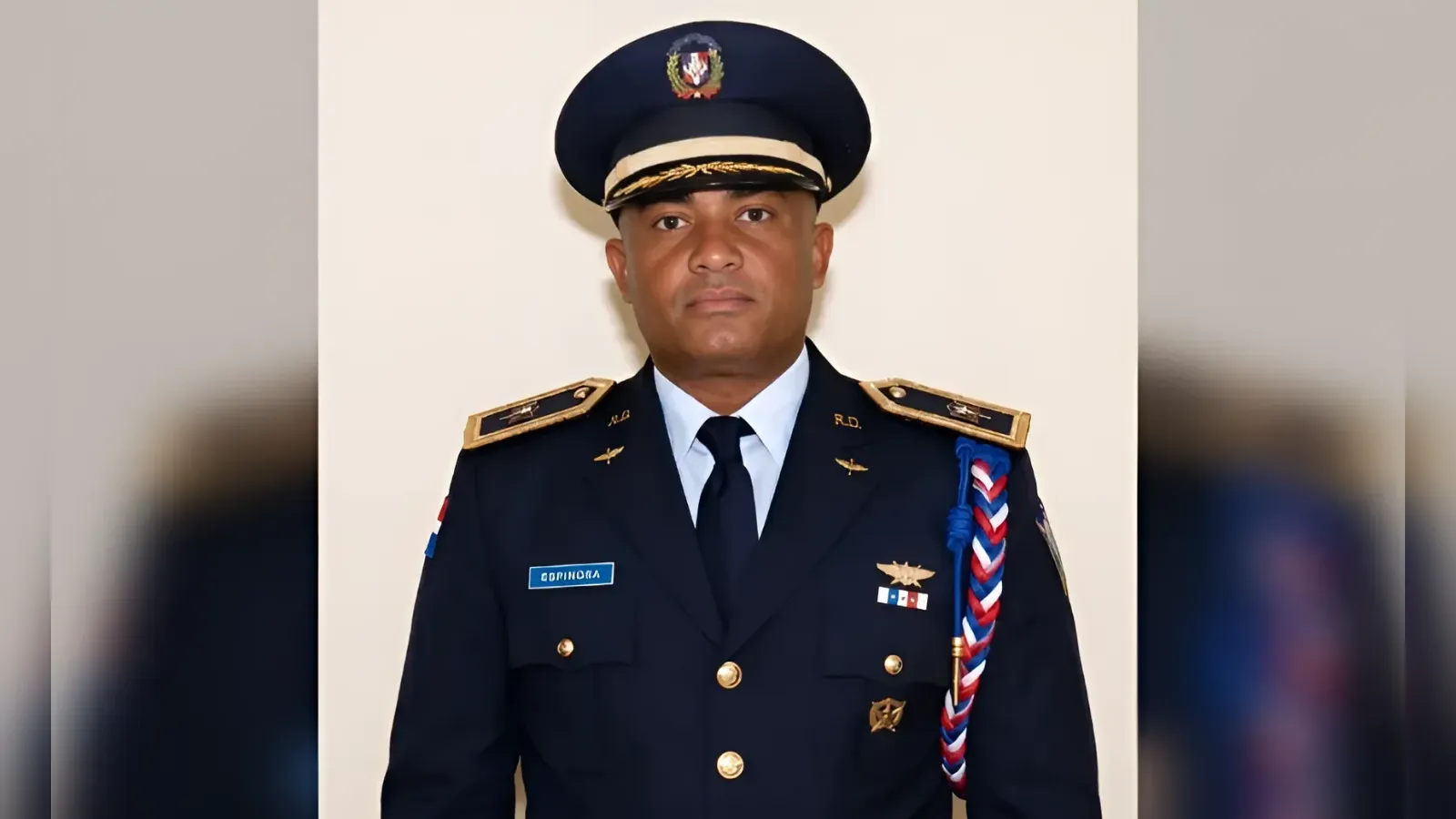 Male military officer in formal dark blue uniform with gold buttons, insignia, and a braided aiguillette, facing the camera.