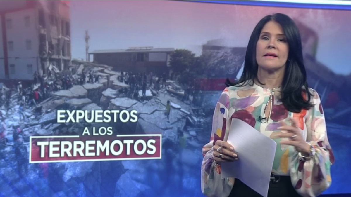 Female news anchor in a studio holding papers, reporting with a backdrop of earthquake-damaged buildings and the text 'Expuestos a los Terremotos'.