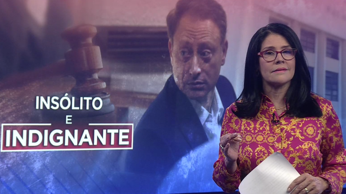 News anchor stands beside a screen showing a gavel and the words 'Insólito e Indignante' in bold, suggesting a crime or odd news segment.