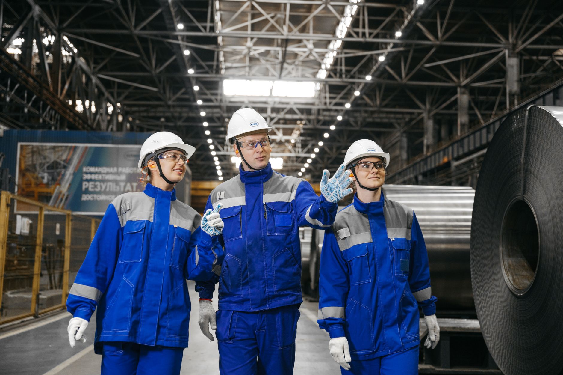 Trabajadores con cascos y uniformes azules conversan en una instalación industrial
