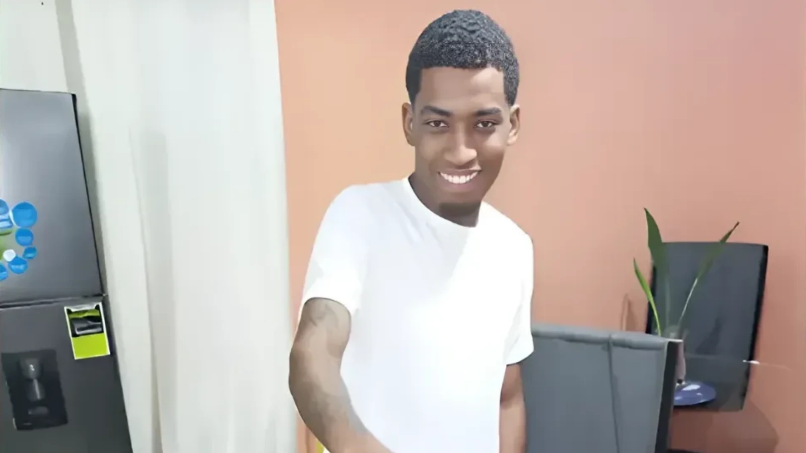 Smiling man in a white shirt taking a selfie in an office.