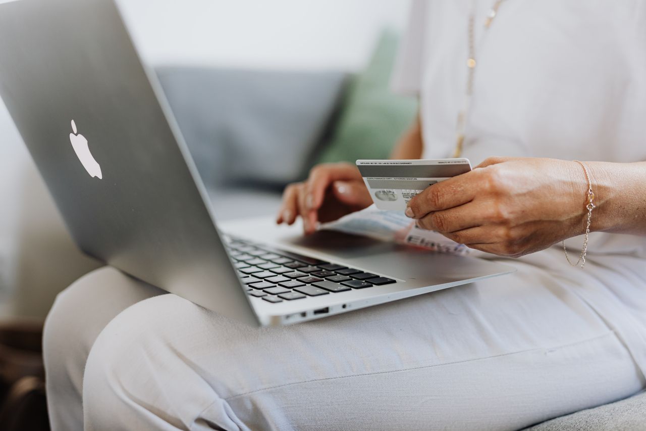 Persona con una tarjeta bancaria usando una computadora en casa