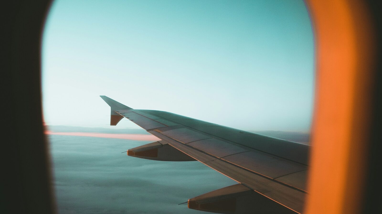 Ala de un avión vista desde una ventanilla sobre el cielo